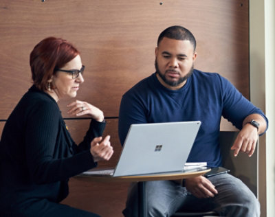 A man and a woman sitting at a table with a laptop.