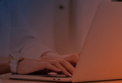 A close-up of a person's hand typing on a laptop keyboard.