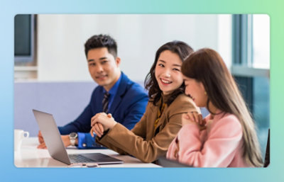 A group of people sitting at a table looking at a laptop.