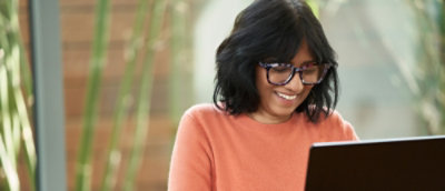 A woman smiling while using a tablet.