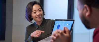 A women showing a laptop screen to a man.
