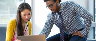 A man and woman looking at a laptop.
