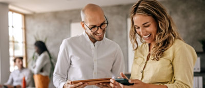 Colleagues in an office checking information on a tablet and phone.