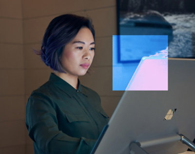 A women looking into a desktop screen and smiling.