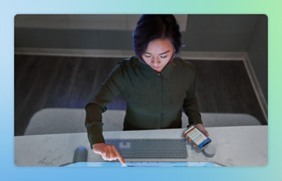 Person using a desktop screen and smartphone at a workspace.
