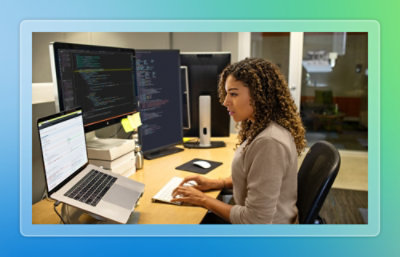 A person sitting at a desk using a laptop on a stand.