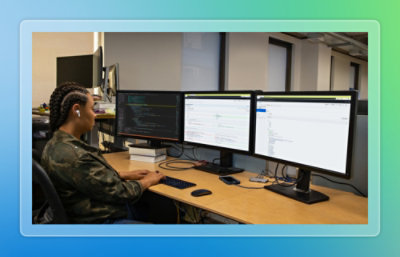 A man sitting at a desk with several computer screens.