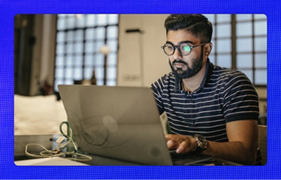 A person wearing glasses using a laptop at a desk.