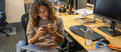 A woman looking at the mobile while sitting in the office environment