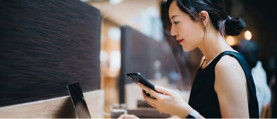 A women working on laptop and holding mobile.