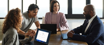 A group of people sitting at a table with laptops.