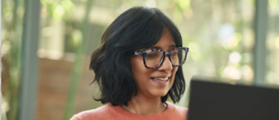 戴眼鏡的女人看著螢幕微笑