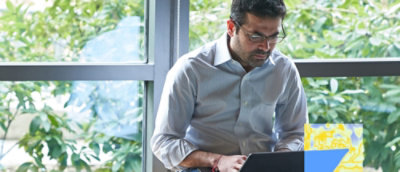 Person using laptop by window with greenery outside