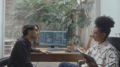 Ein Mann und eine Frau, die auf einen Computerbildschirm blicken.