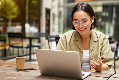 Eine Frau mit Brille, die auf einen Laptop blickt.
