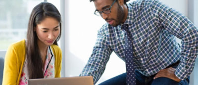 Ein Mann und eine Frau, die auf einen Laptop schauen und diskutieren