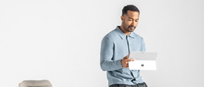 Ein Mann, der neben einem Tisch steht und ein Tablet hält.