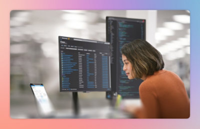 コンピューターの画面を見ている、オレンジのシャツを着た女性