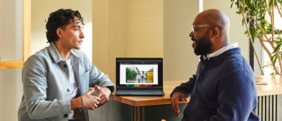 ノート PC を見ながら話す数人の男性。