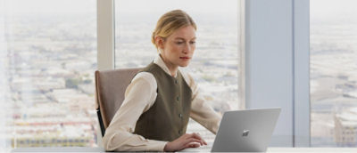 Žena, která sedí u stolu s notebookem.