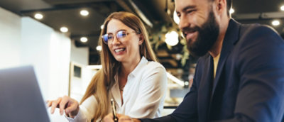 A man and woman looking at the laptop and smiling