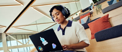 A person wearing headphones and looking at a laptop.
