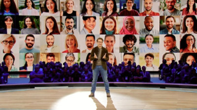 A man standing at a podium, in the background multiple pictures are displayed on the screen.