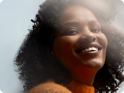 A woman wearing orange sweater and smiling