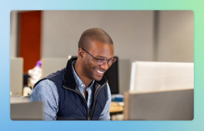 Мужчина улыбается, глядя на экран компьютера