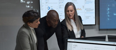 Мужчина и две женщины вместе смотрят на планшет.