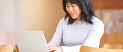 A woman using a laptop at a desk in a modern office setting.