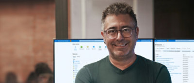 A man with glasses stand infront of desktop.
