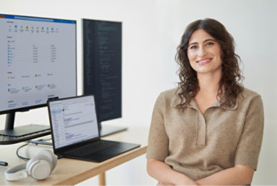 A woman sitting beside screens and smiling