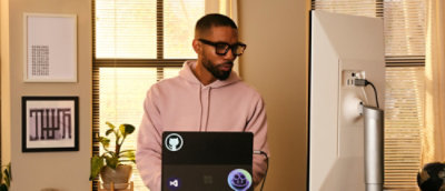 A man wearing glasses and working on the laptop