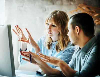 A man and woman looking at a computer screen.