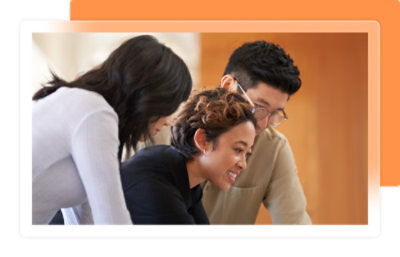 Three people collaborating closely while looking at something on a desk.
