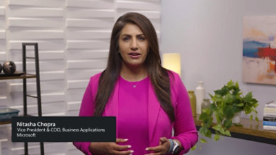 Person in a bright pink outfit standing indoors with a modern background and a text overlay displaying name and title.