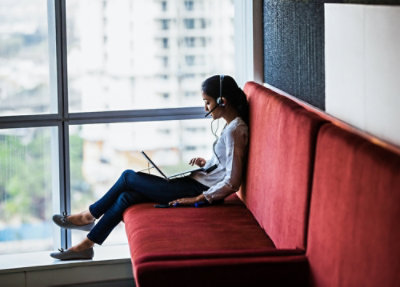 A woman wearing a headset while working on a laptop.
