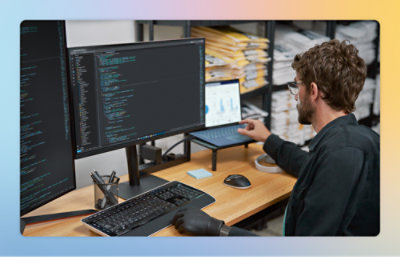 En mand sidder ved et skrivebord og bruger en bærbar computer med tekst på skærmen.