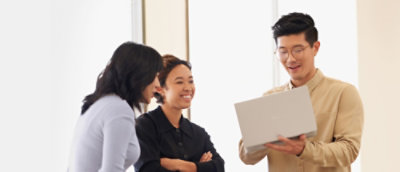 A group of people standing around a laptop.