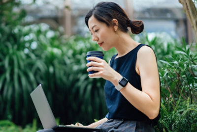 一个人拿着杯子看着笔记本电脑。