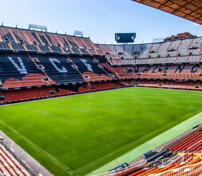 The inside of a soccer stadium with an orange field.