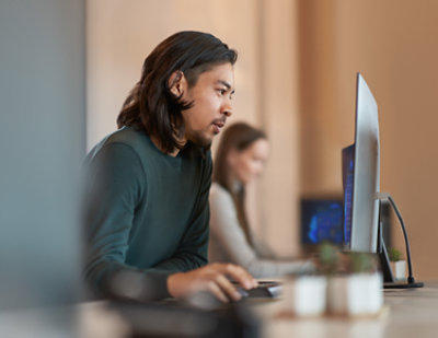 A man in a green shirt sitting at a table with a computer.