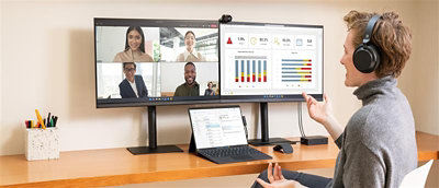 A man on a desk with two monitors in front of him.