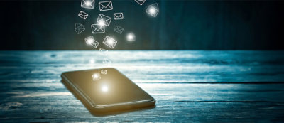 Uno smartphone posato su un tavolo con icone luminose che sembrano messaggi fluttuanti