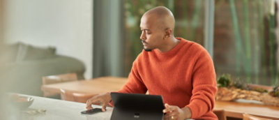 Egy férfi a mobilképernyőt nézi, miközben a másik kezében táblagépet tart