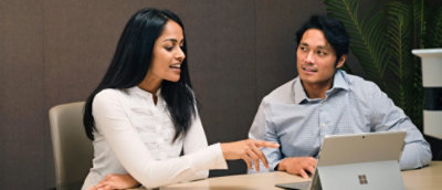 Egy nő magyaráz, miközben a képernyőre mutat egy férfinak