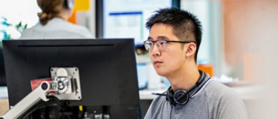 Egy szemüveges férfi, aki egy asztali számítógépet néz