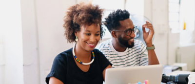 Une femme aux cheveux courts et bouclés, souriante, et un homme assis à côté d'elle