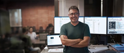 קבוצה של חמישה אנשים עומדים סביב שולחן עם מחשב נישא במשרד מואר. 